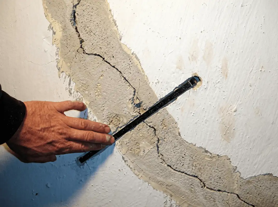 A wall with a large crack is being inspected by a professional in Cleveland, OH