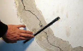 A wall with a large crack is being inspected by a professional in Cleveland, OH